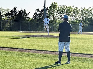 Under the watchful eye of the Father Tolton first base coach, Helias pitcher Trey Rice warms up in the seventh inning of Wednesday night's game at the American Legion Post 5 Sports Complex. (Tom Rackers/News Tribune)
